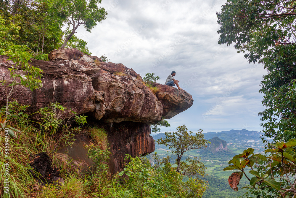 独自一人坐在悬崖边欣赏位于考的雨林龙冠