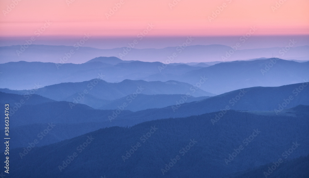 Mountain ridges in fog at sunset in autumn. Beautiful landscape with foggy mountain valley, rocks, f