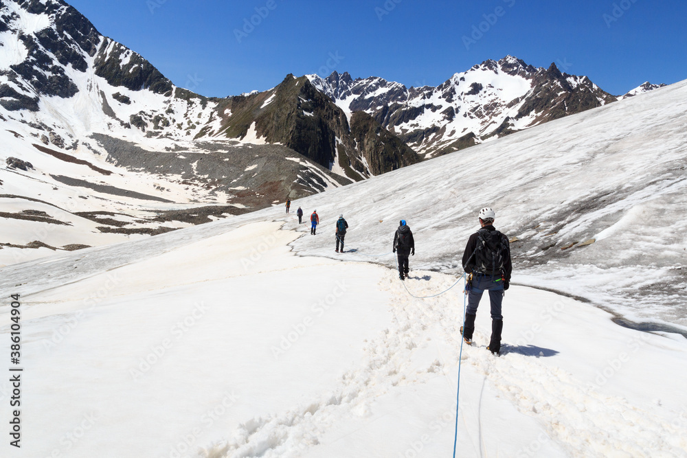 Rope team mountaineering with crampons on glacier Taschachferner and mountain snow panorama with blu