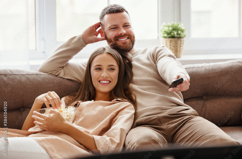 Family couple watching television at home on sofa.