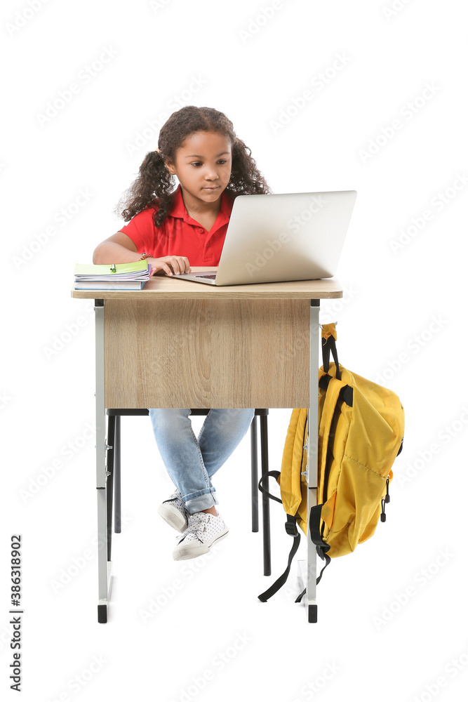 白人背景下，一名非裔美国女学生拿着笔记本电脑坐在学校桌子旁