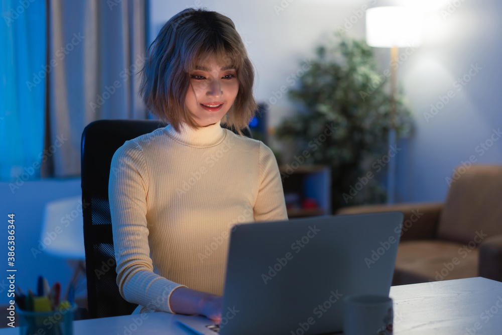 Asian woman Use your computer to play social network at night at her home.