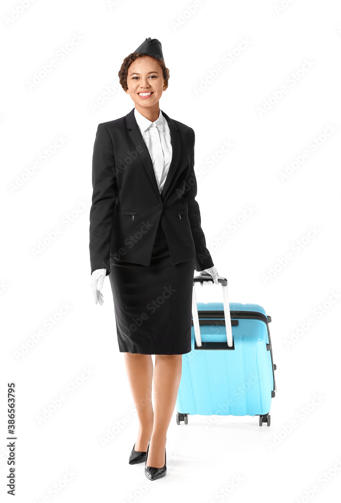 Beautiful African-American stewardess with luggage on white background