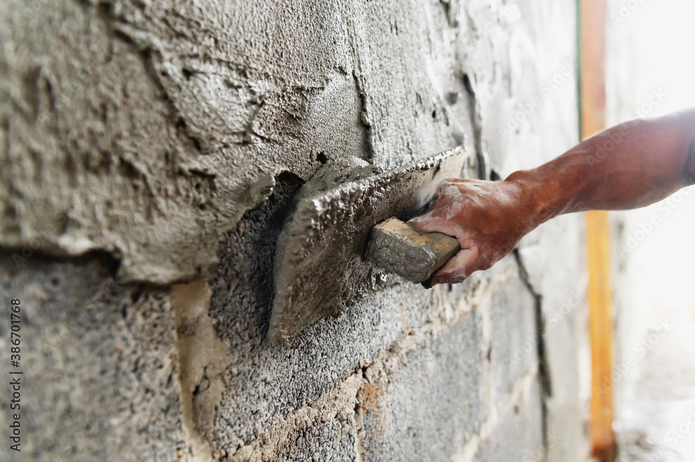 closeup hand of worker plastering cement at wall in construction site