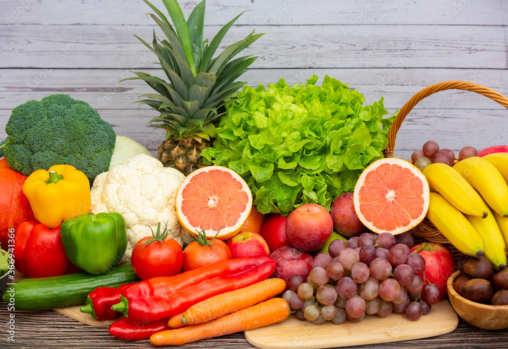 将蔬菜和水果苹果、葡萄、橙子和香蕉与胡萝卜一起放在木篮子里。