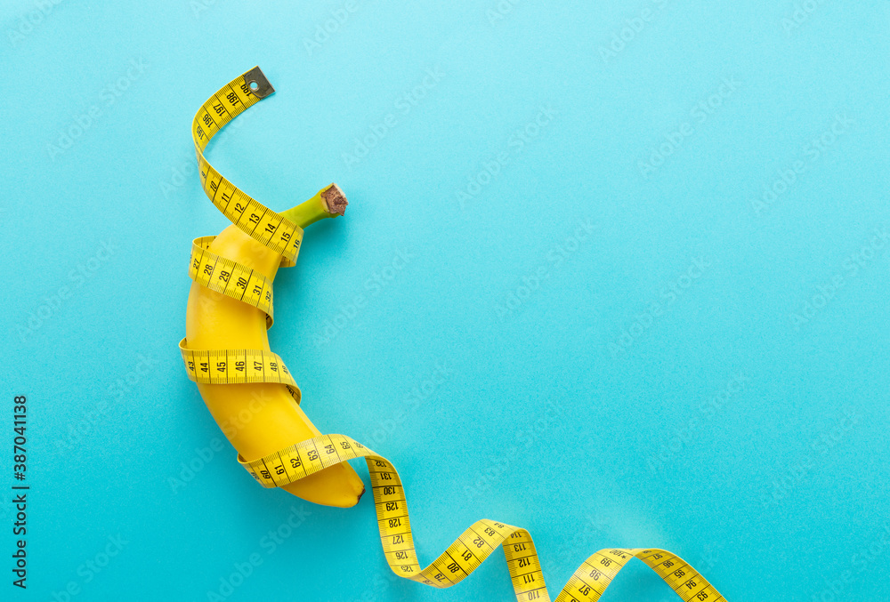 A banana with a measuring tape wrapped around a blue background