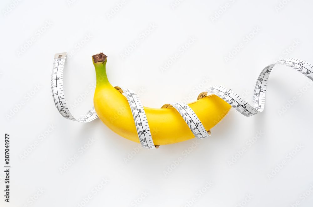 A banana with a measuring tape wrapped around a white background