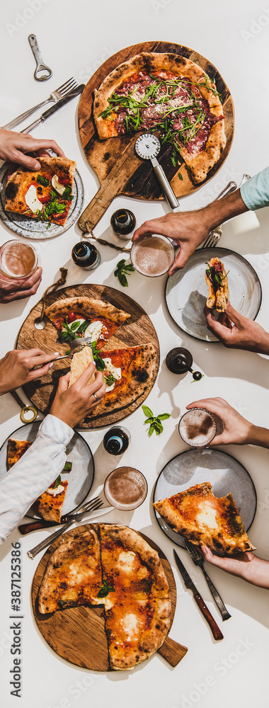 Pizza party for friends or family. Flat-lay of various pizzas, lager beer and people eating pizza ov