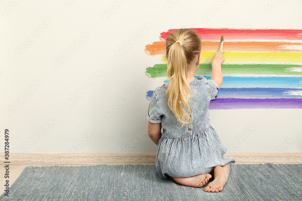 可爱的小女孩在墙上画彩虹