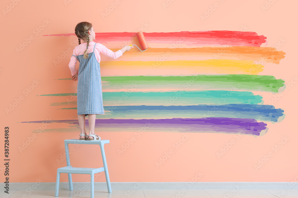 Cute little girl painting rainbow on wall