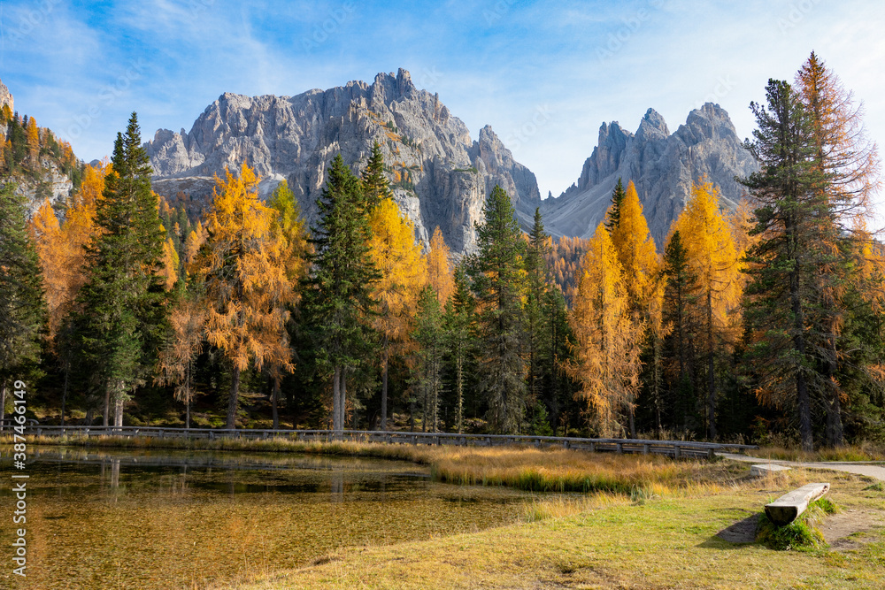 Scenic trail runs around a tranquil lake in the autumn colored Italian Alps.