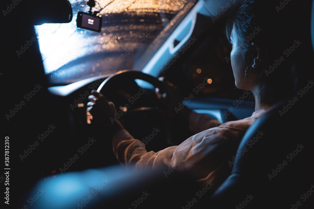 一个亚洲女人在夜里独自开车。天在下雨。