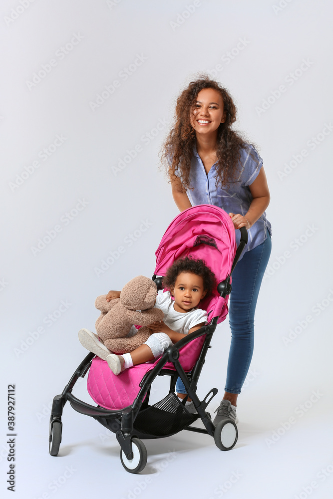 浅背景下，一名非洲裔美国妇女和她婴儿车里的可爱婴儿