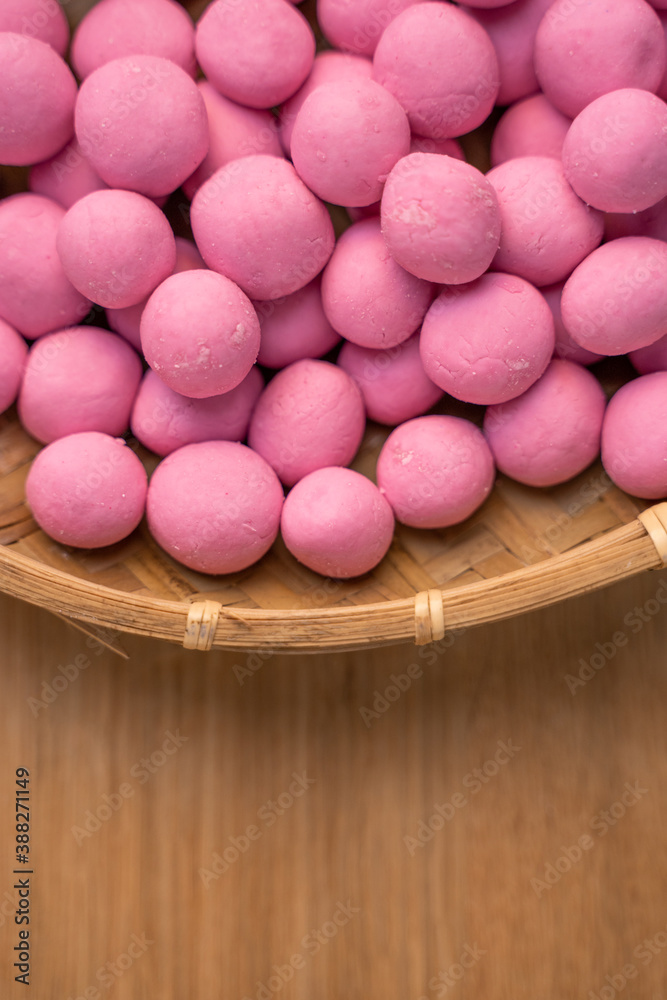 Raw little tangyuan in a sieve over wooden table.