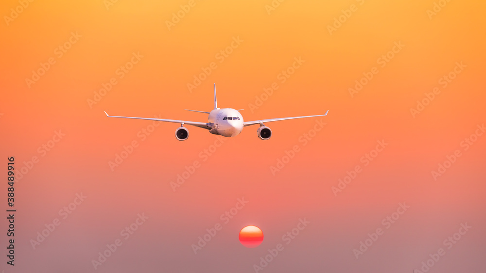 Commercial airplane flying above clouds in sunset.