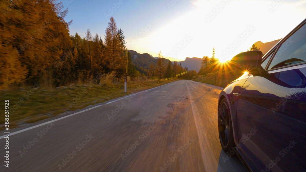 特写：一辆蓝色汽车在日出时沿着风景优美的道路行驶的电影镜头。