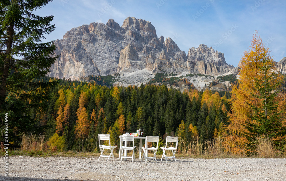 Picnic table stands full underneath a scenic rocky ridge in the Italian Alps