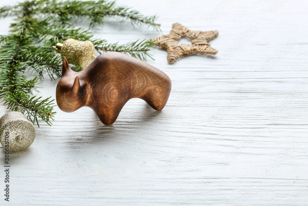 Figurine of bull and New Year decor on white wooden background