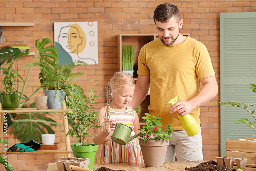 Young father with daughter setting out plants at home