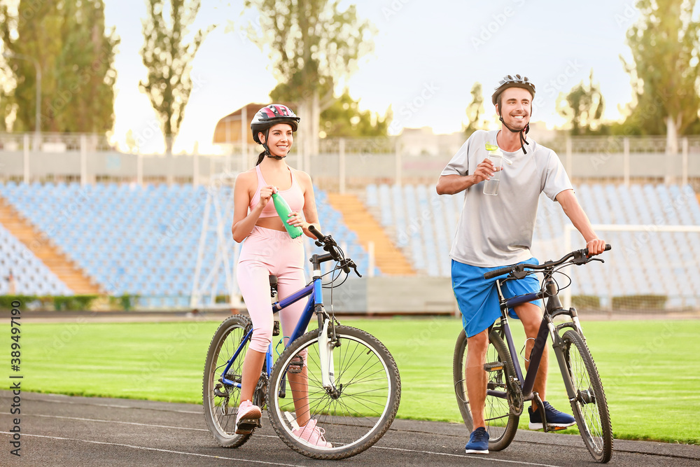 Sporty young cyclists drinking water at the stadium