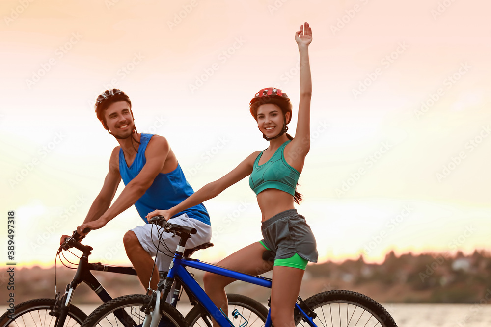 Sporty young cyclists riding bicycles near river