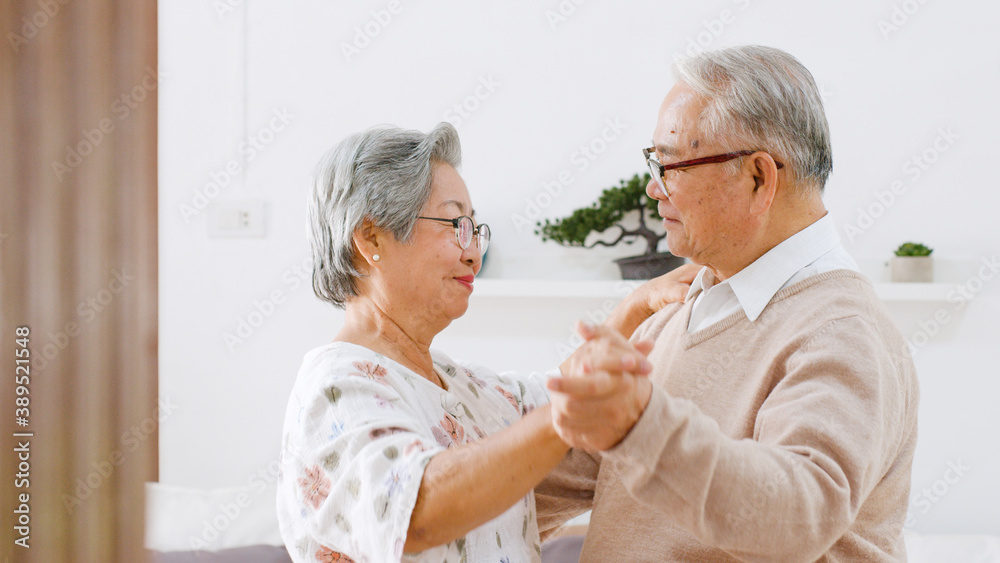 Asian senior couple enjoy dancing to relax at home, senior retirement lifestyle concept