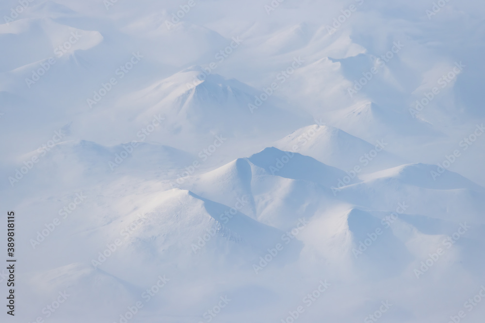 Aerial view of snow-capped mountains and clouds. Winter snowy mountain landscape. Icheghem Range, Ko