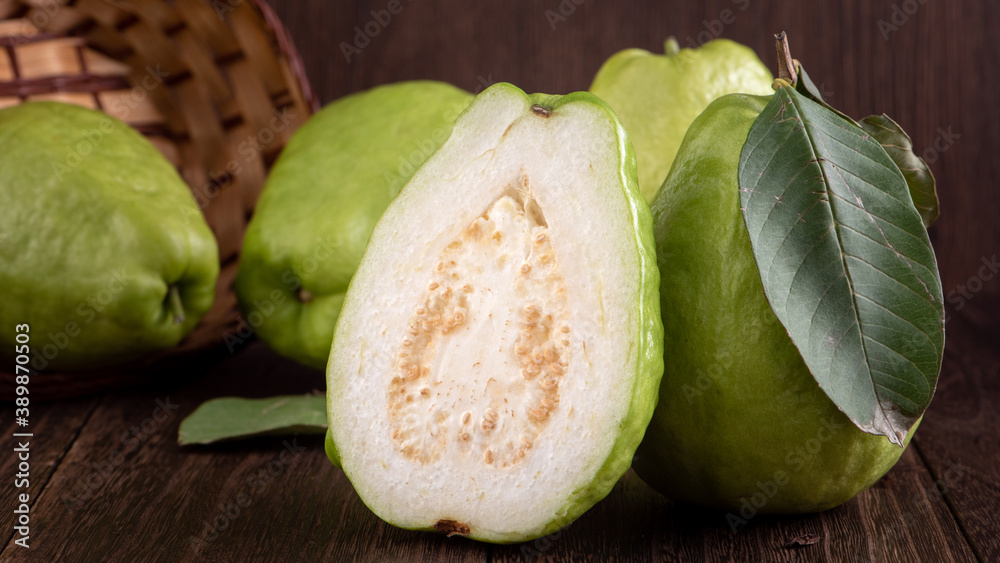 Close up of delicious guava with fresh green leaves on wooden background.