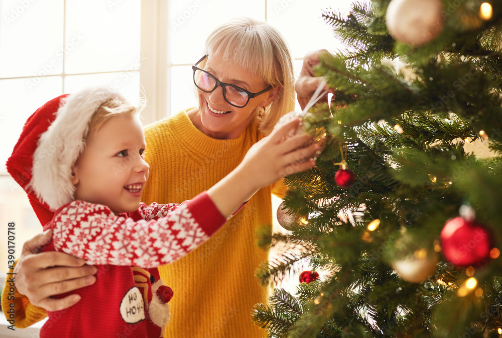 幸福家庭的祖母和孙子为节日装饰圣诞树。