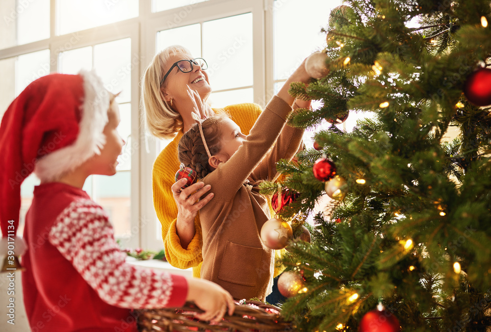幸福的家庭祖母和孙子孙女为节日装饰圣诞树。