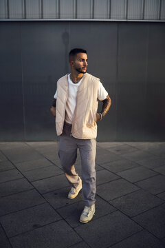 Vertical shot of a young cool male with a street style outfit posing