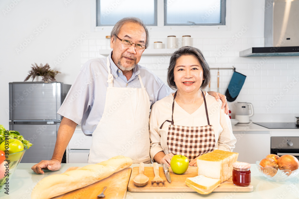 亚洲祖父母夫妇站在厨房里微笑的肖像