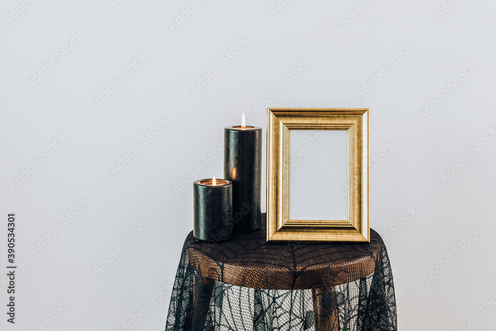 黑色燃烧的蜡烛在蜘蛛蕾丝桌布上的金色相框