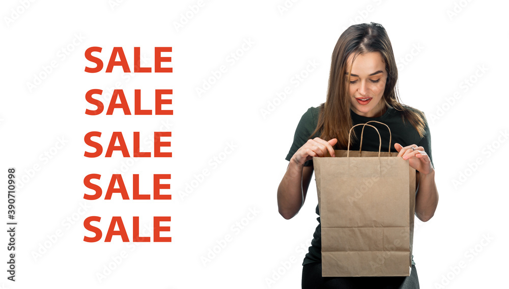 女人拿着白色背景的杂货购物袋。女人看着浅棕色的纸袋i