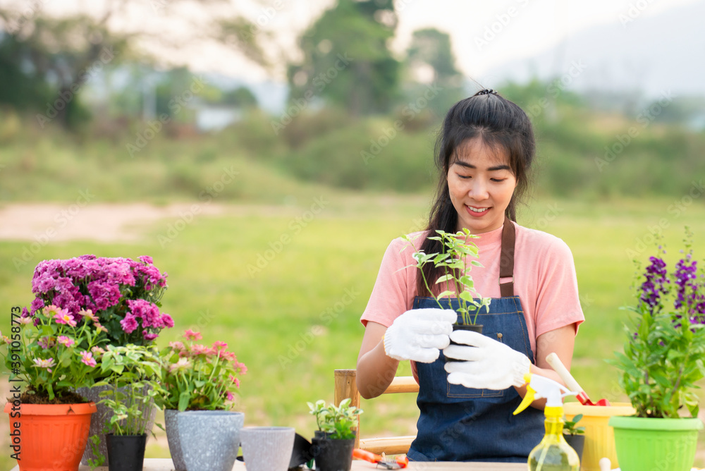 戴着手套的亚洲年轻女子在户外花园里种花