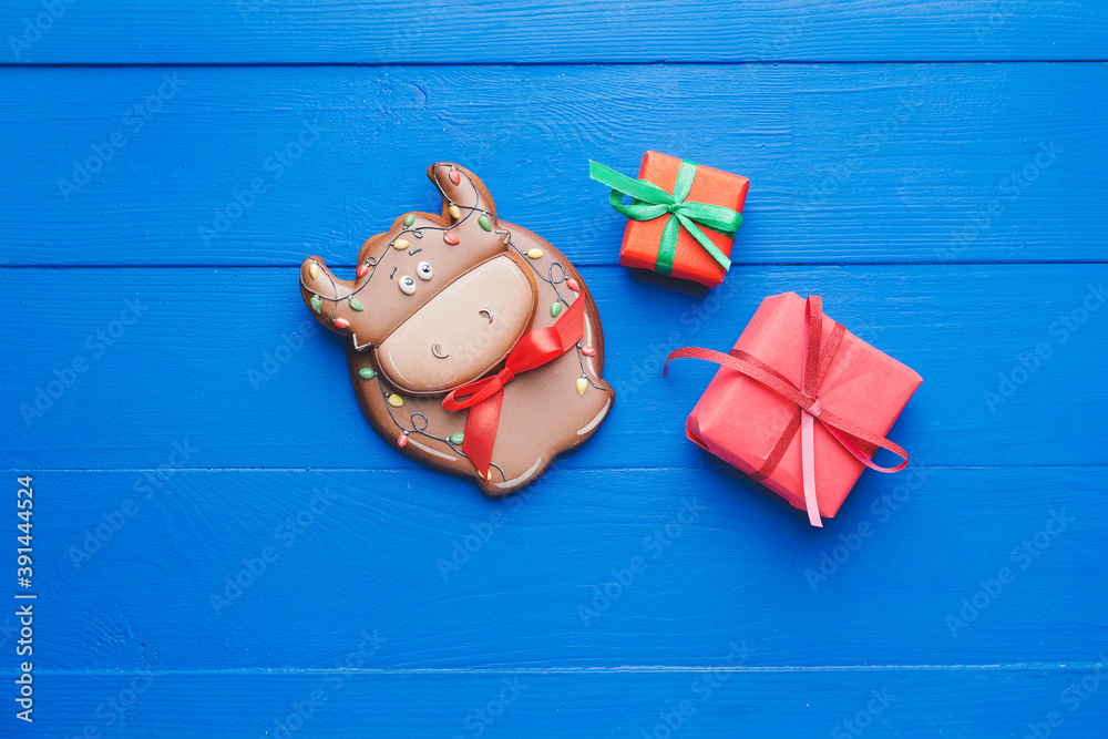 公牛形状的美味饼干和彩色木制背景的圣诞礼物