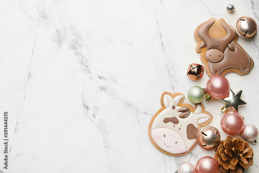 公牛形状的美味饼干和浅色背景上的圣诞装饰