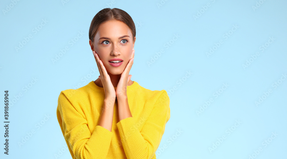 一个穿着蓝色背景黄色毛衣的快乐的、情绪激动的女人。