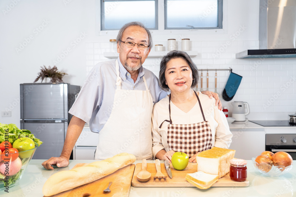 亚洲祖父母夫妇站在厨房里微笑的肖像