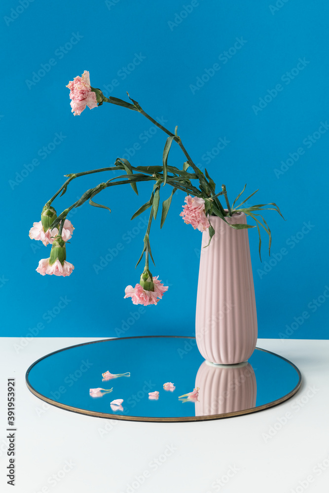 枯萎的粉色康乃馨放在闪亮托盘上的粉色花瓶里