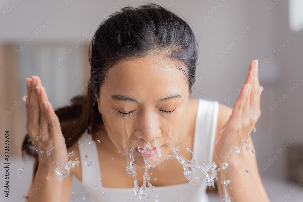 美丽的亚洲女性用水洗脸洗脸。