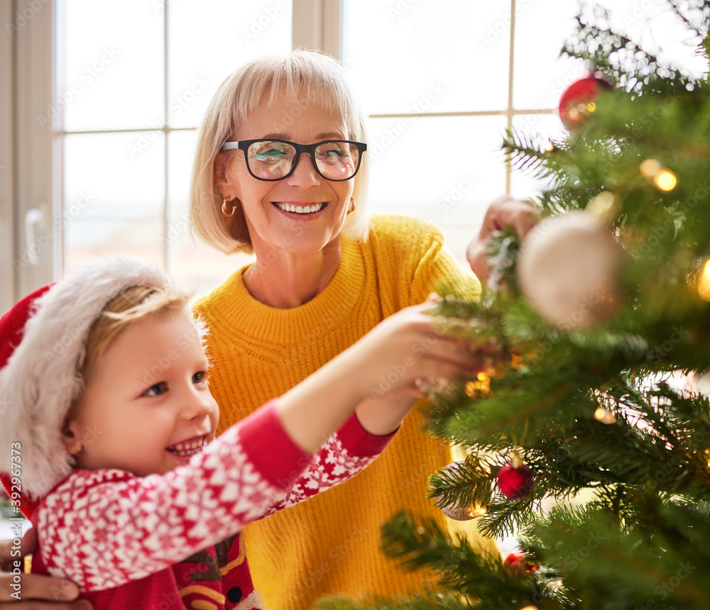 幸福的家庭祖母和孙子为节日装饰圣诞树。