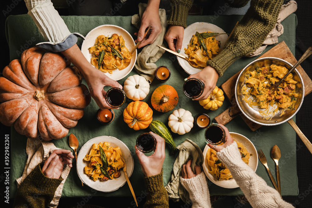 Flat-lay of Autumn dinner for gathering or Thanksgiving Day celebration. Friends clinking glasses wi