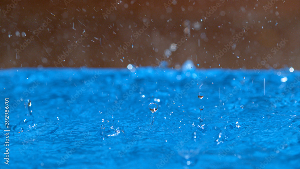 MACRO：雨水与浅蓝色池水接触后飞溅。