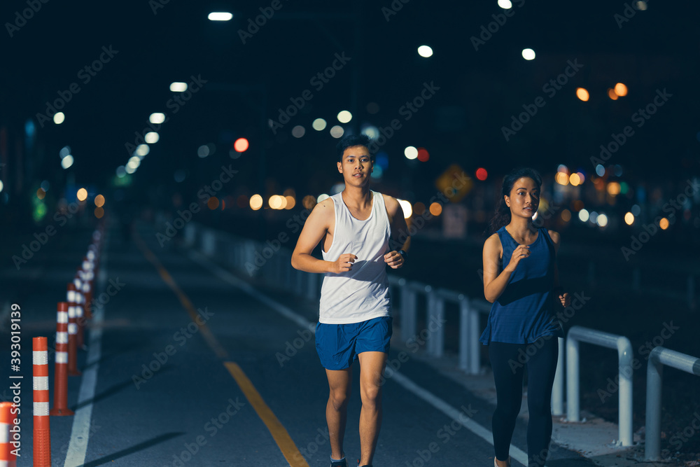 亚洲夫妇晚上在城市街道上慢跑