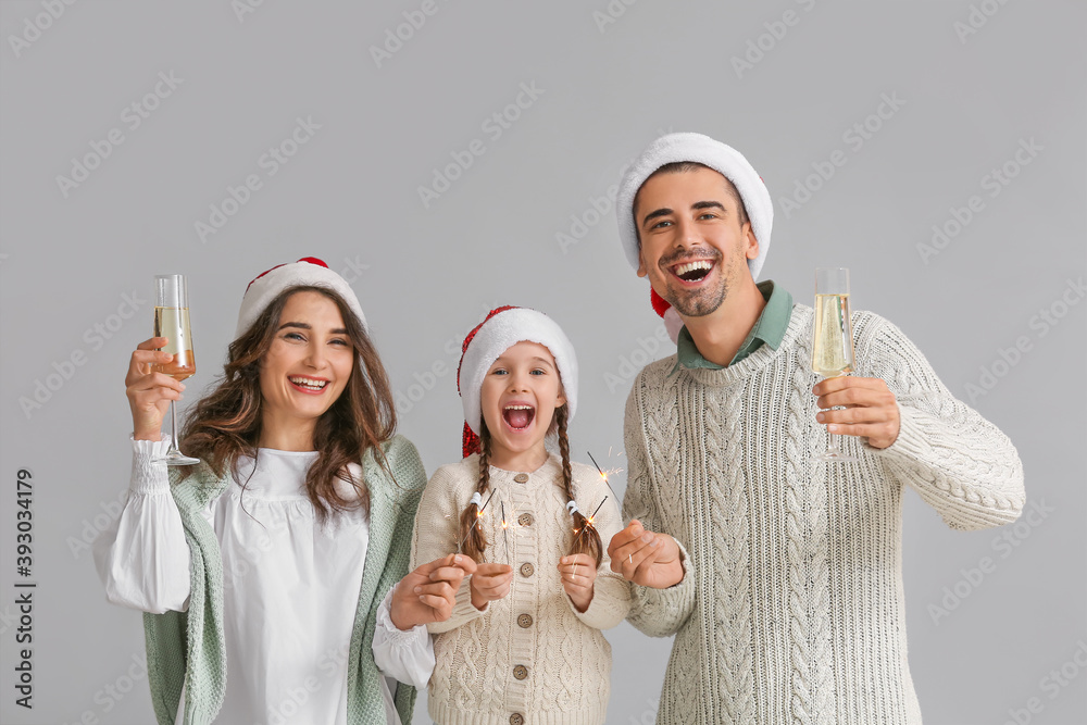 Happy family with Christmas sparklers and champagne on grey background