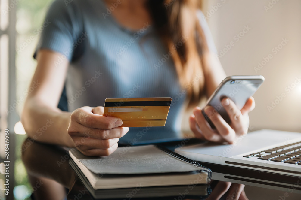 女商人手动使用智能手机、平板电脑支付和持有信用卡在线购物，无处不在