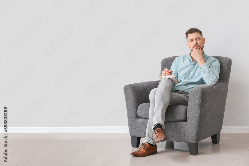 男心理学家坐在靠近光墙的扶手椅上