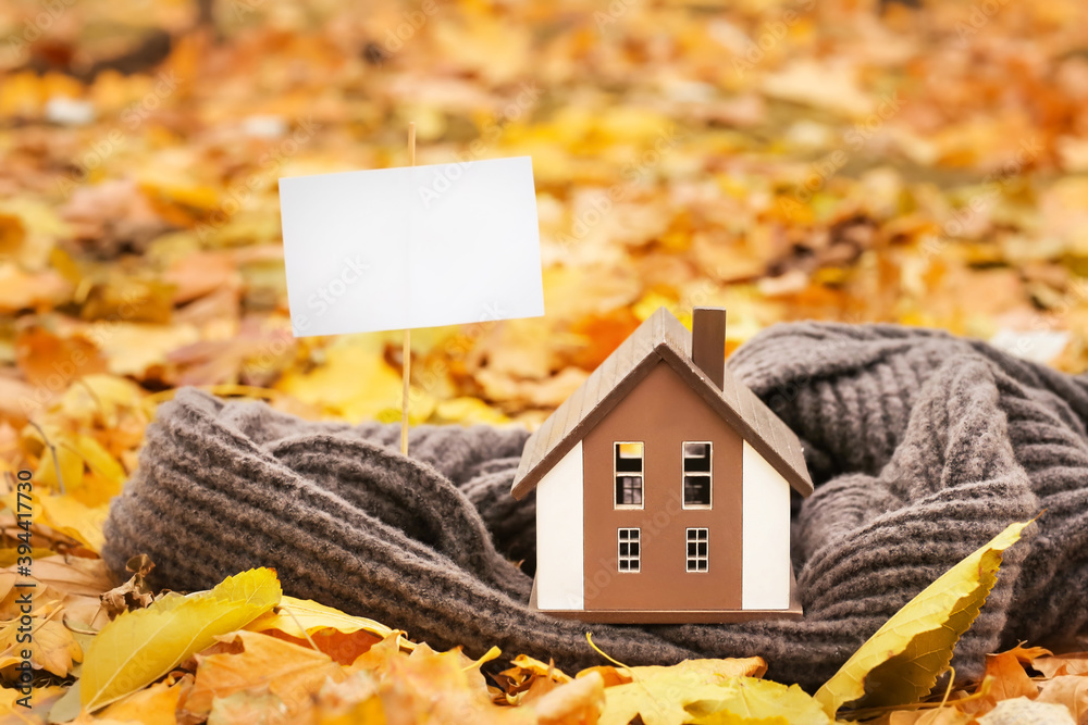 秋天公园里的房子、棍子上的空白纸和温暖的围巾。供暖季节的概念