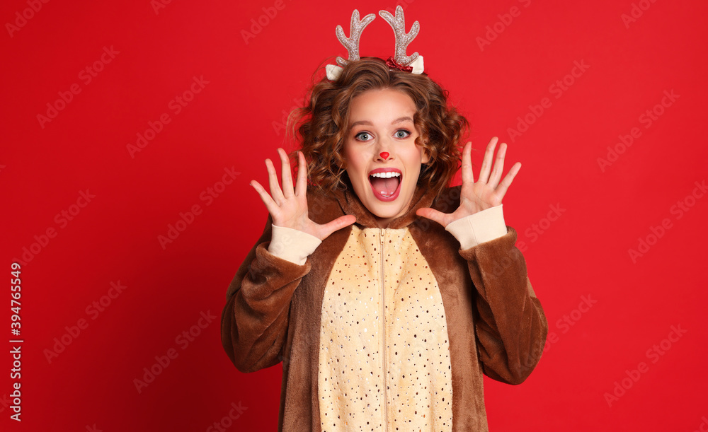 身着圣诞驯鹿服装的快乐女人在五颜六色的红背上充满喜悦和赞美
